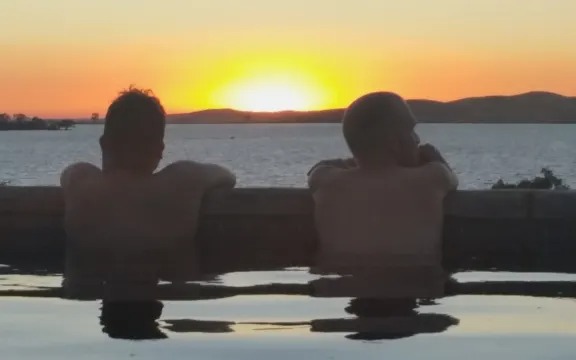 Two men watching the sunset over the lake from the pool
