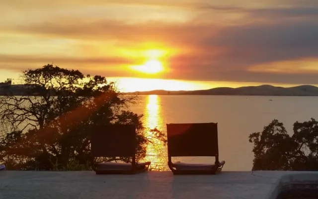 Lounge chairs silhouetted against the sunset over Lake Millerton