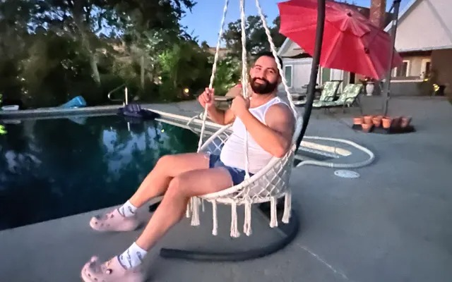 Guest relaxing in a hanging swing chair by the pool at dusk