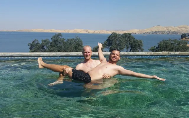 Two men floating together in the pool